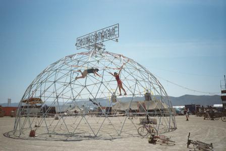 Two monkeys climb the extremely large jungle gym.